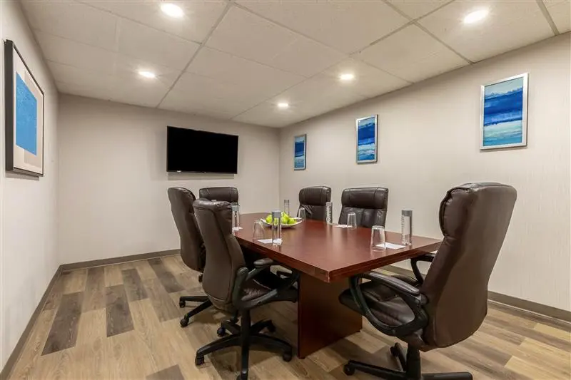 Conference room with large wooden table, brown chairs, and flat-screen TV.