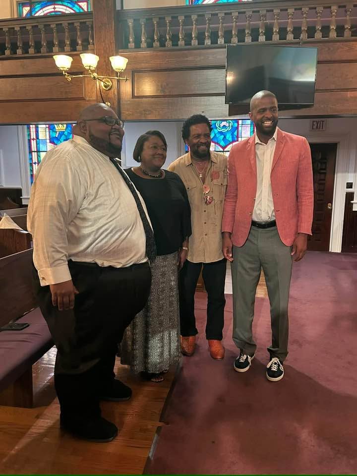 Representative Wendell Gilliard standing with community members inside a church.