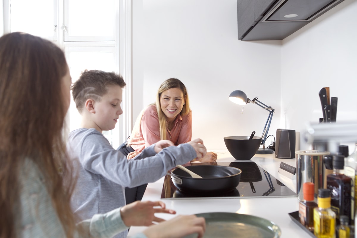 Mom and two kids cooking together in a vacation rental kitchen on a family summer trip