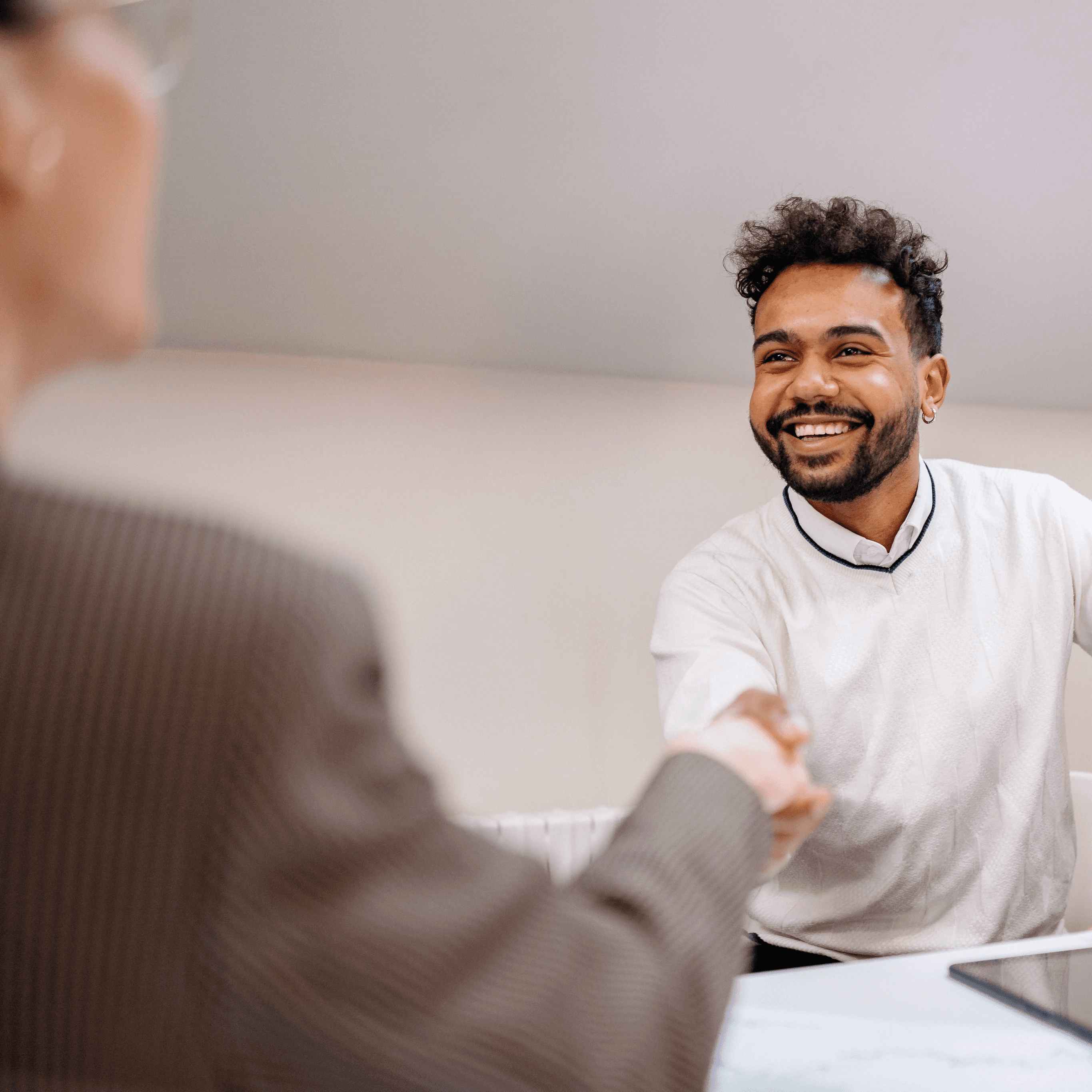 Smiling HR professional shaking hands with an employee, exemplifying successful talent retention strategies in the workplace.