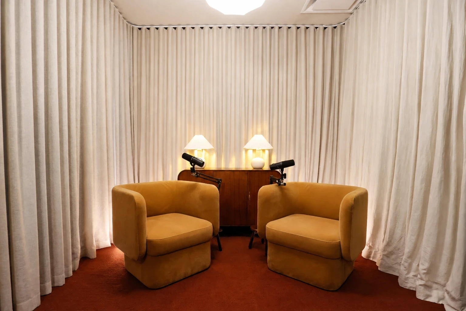 COVE – Collingwood: two mustard armchairs with microphones and lamp-lit cabinet