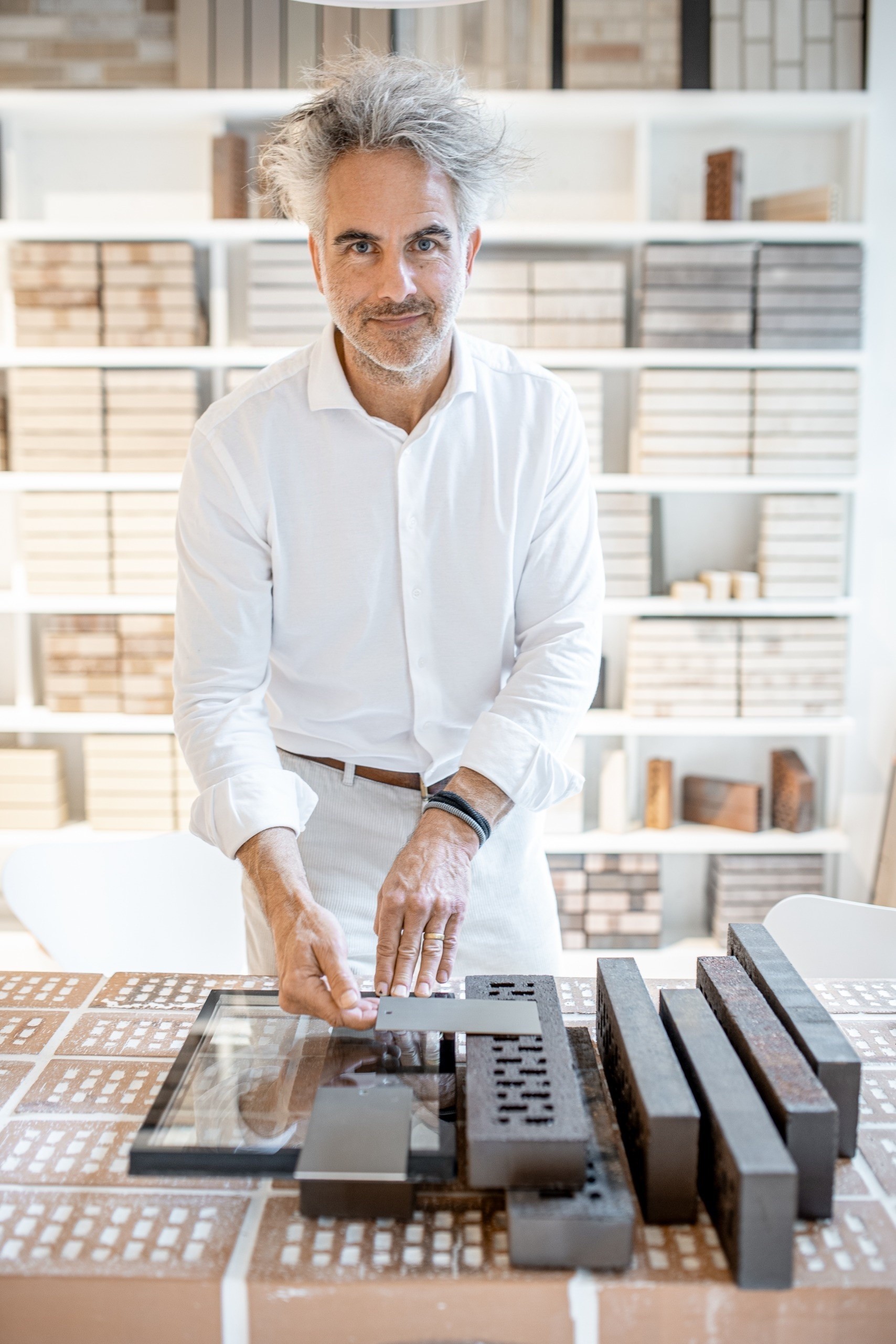 Man met grijs haar staat achter een tafel met stenen