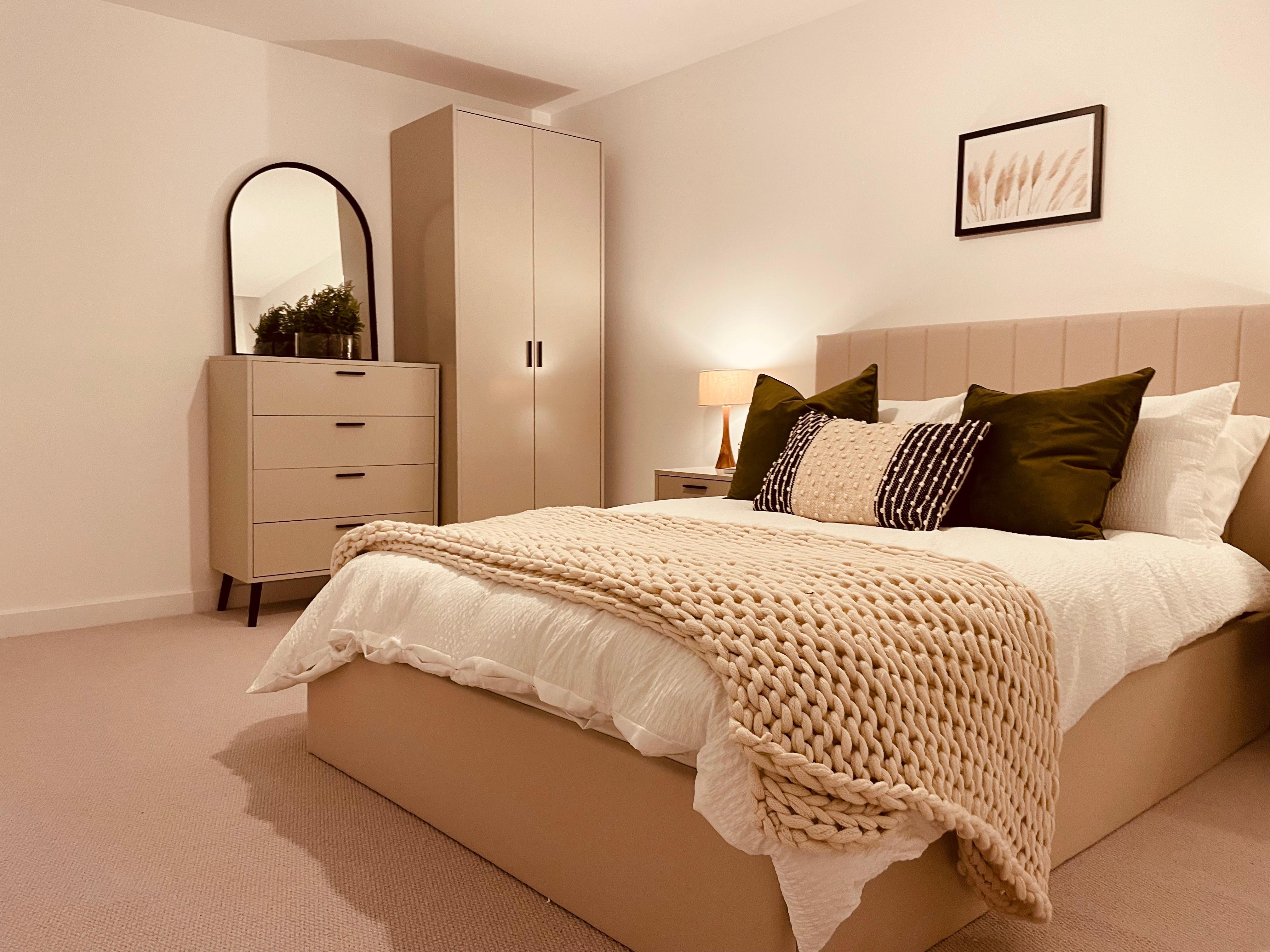 Bedroom with neutral furniture and arched mirror in Leeds show home design