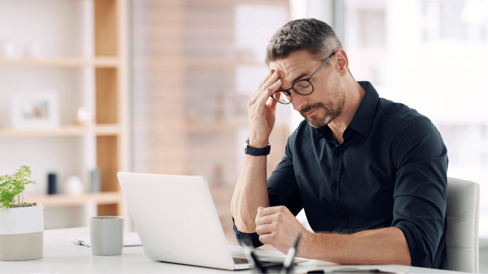 A winding road cuts through rocky terrain, surrounded by patches of green grass and illuminated by sunlight.