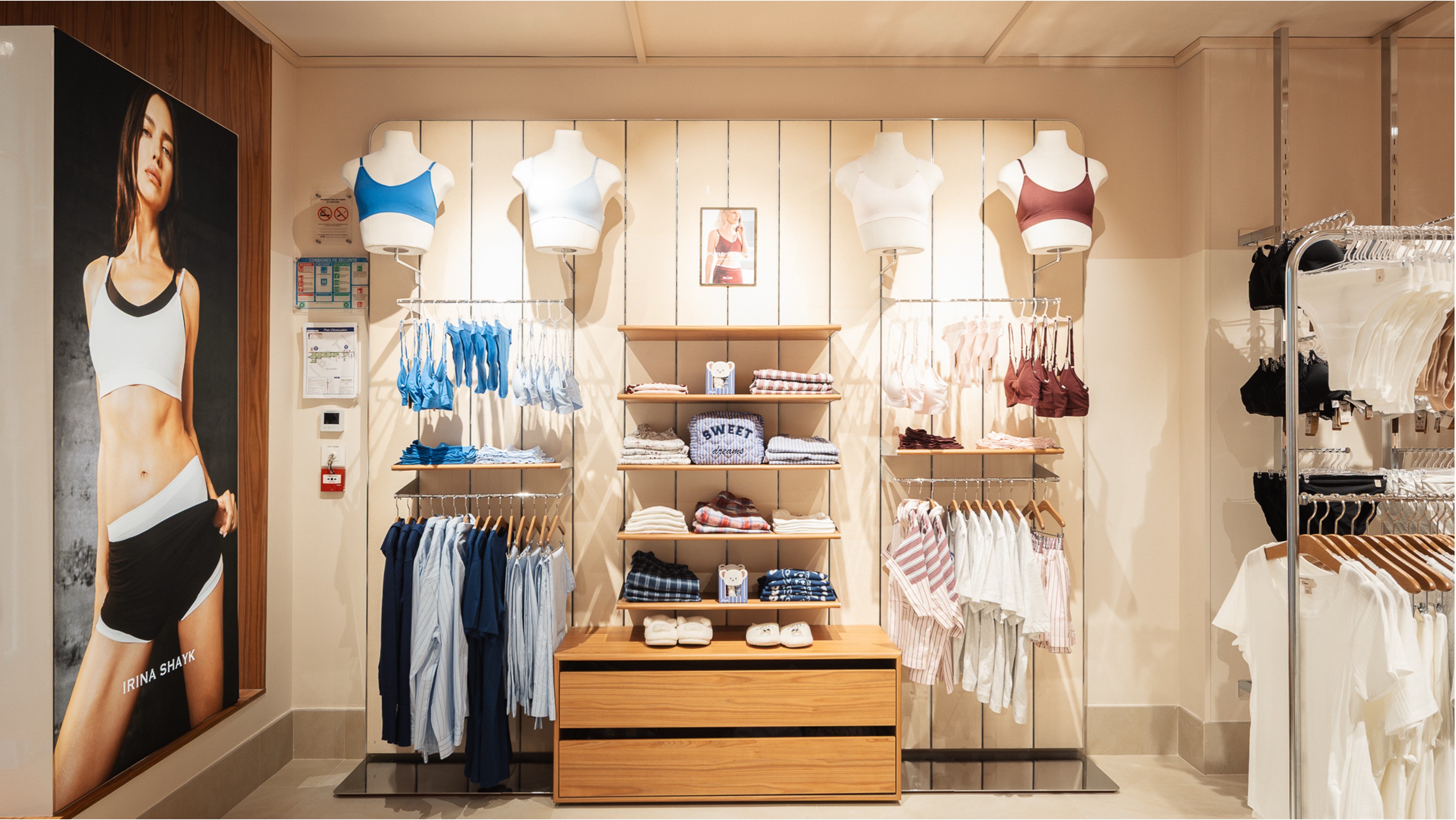 Vitrine de lingerie sportive et pyjamas, mannequins bustes, affiche 'IRINA SHAYK', étagères bois clair