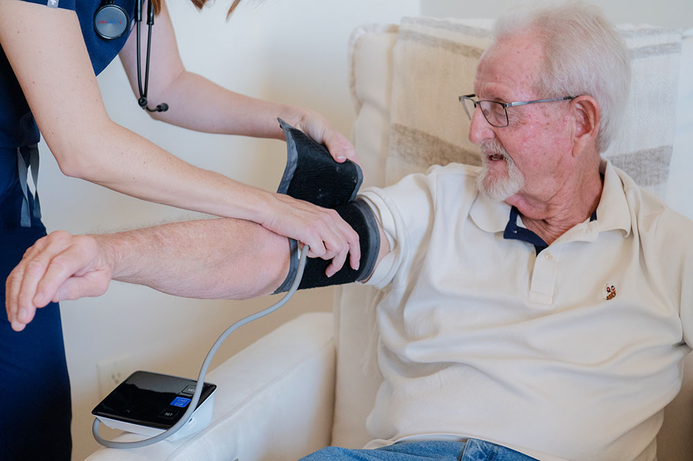 Nurse putting a blood pressure cuff on client.