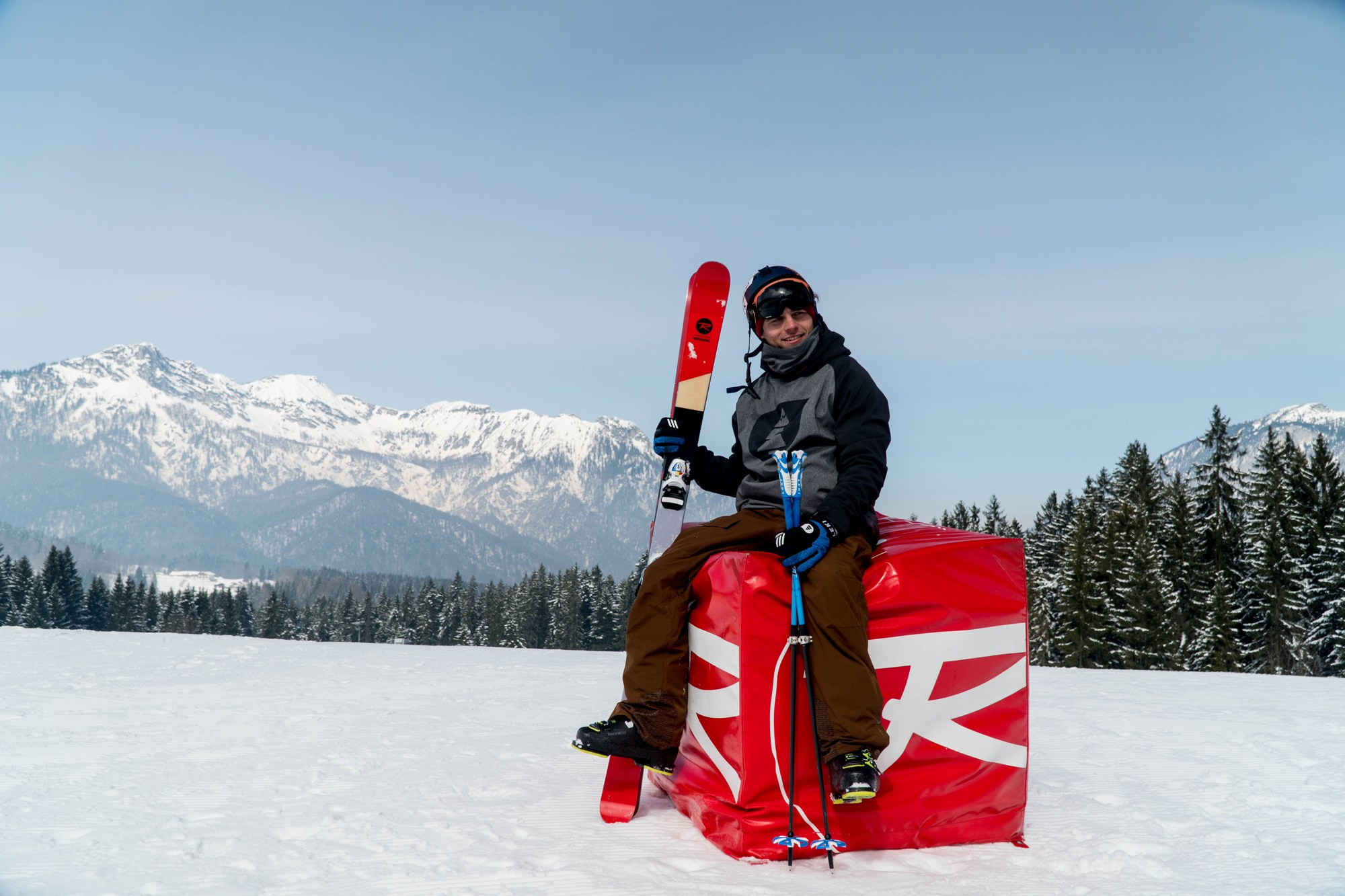 Tobi Deckert on a Rossignol banner in the snow, skis in hand — material sponsorship means supporting the gear visibly and credibly