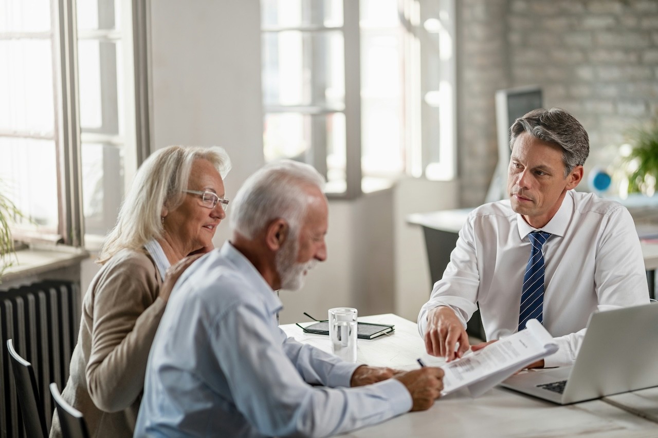 An older couple signing a contract with an M&A Consultant