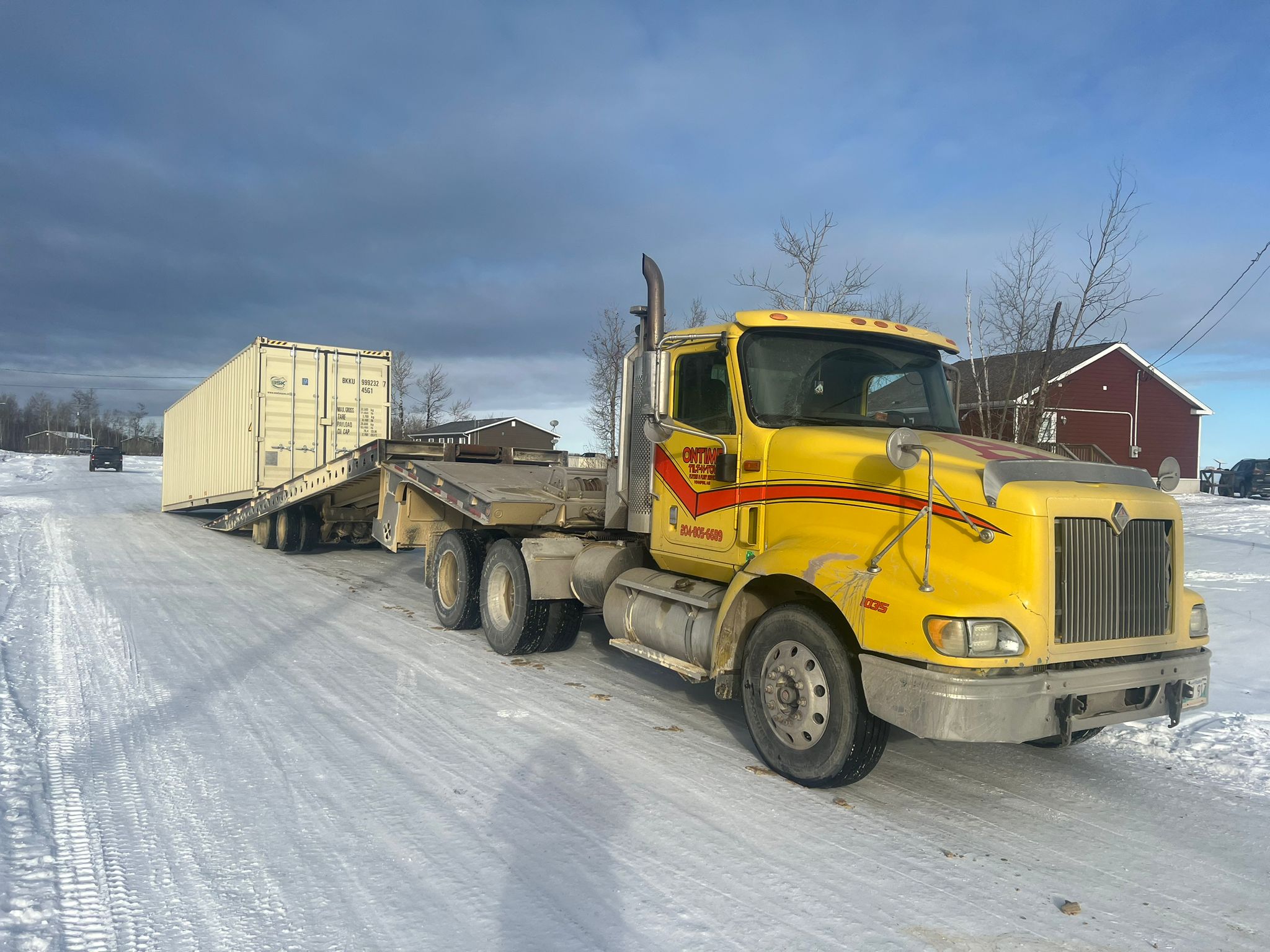 New (1 trip) 40-foot beige high cube container drop off with a semi truck and tilt deck trailer