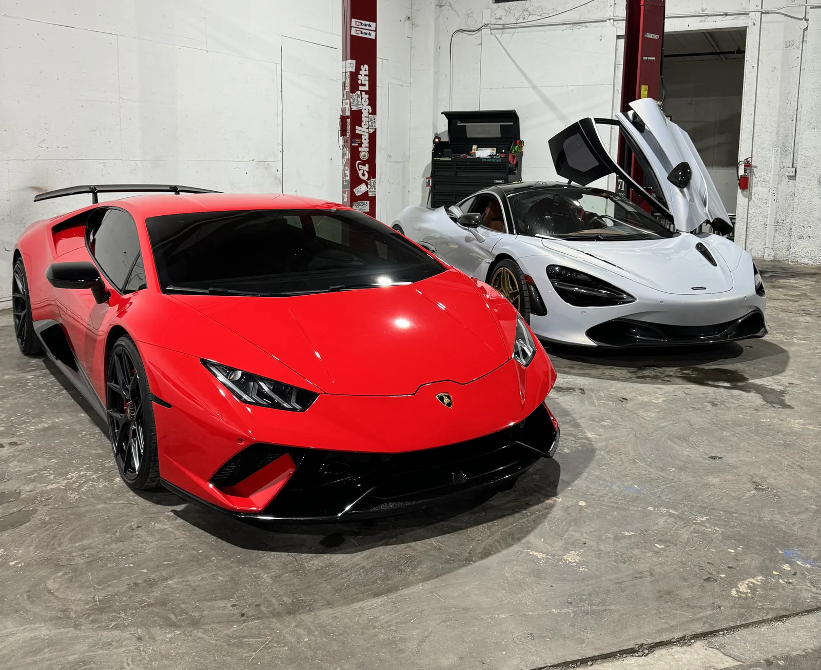 Red Lamborghini Huracán and a McLaren in the 714 Technik service bay