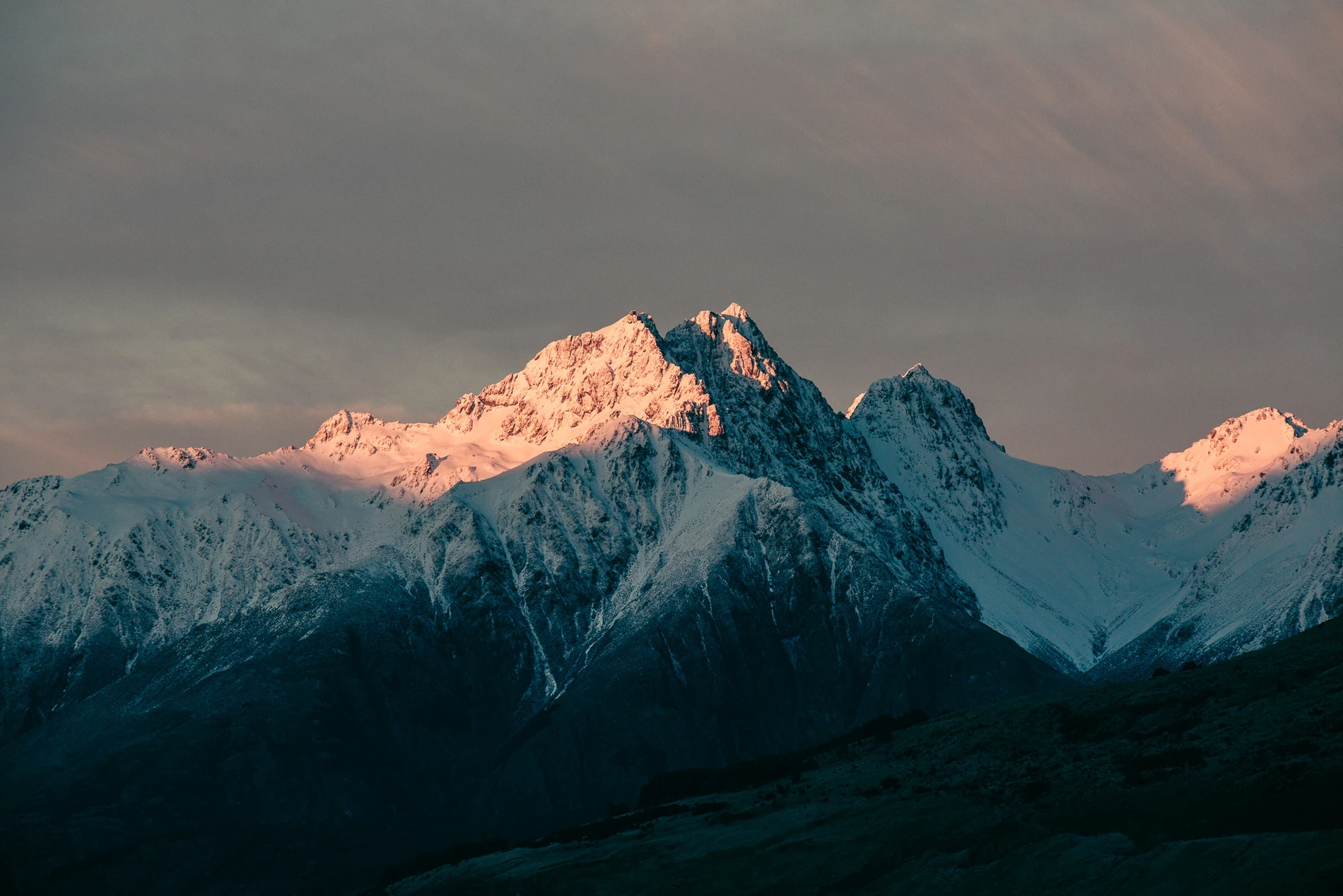 First light catching the summits of a dark, steep mountain range