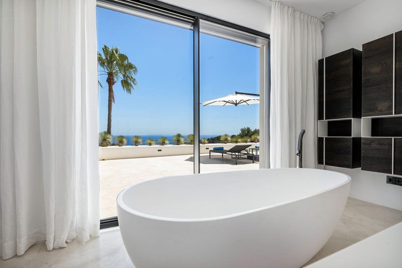 Luxury suite bathroom with freestanding bathtub and floor-to-ceiling windows overlooking the Mediterranean Sea.