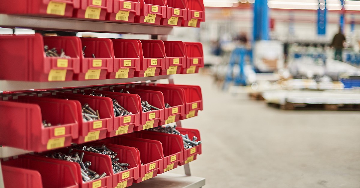Rote Lagerbehälter gefüllt mit Schrauben in einer Fabrikhalle. Industrielle Lagerung.