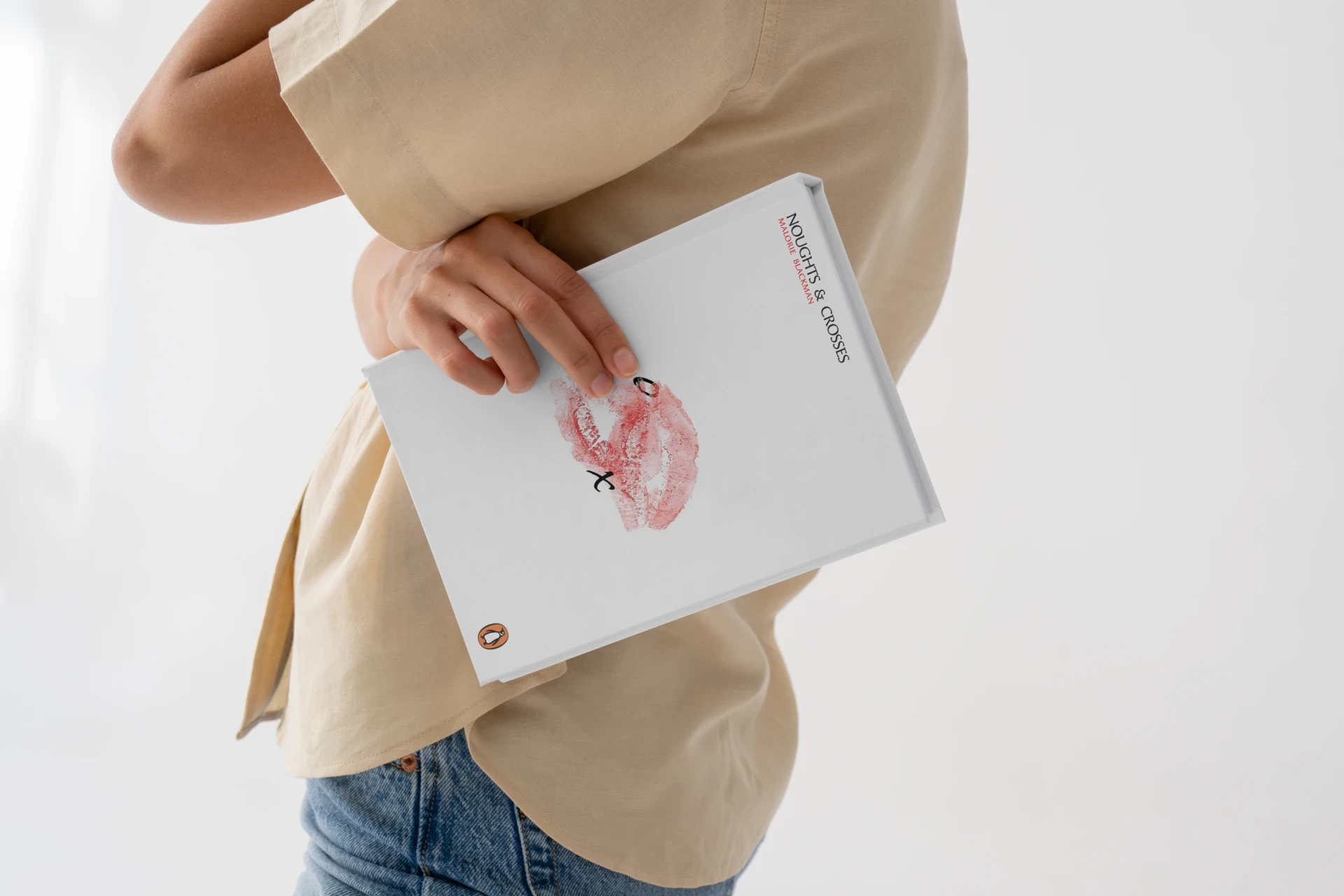 Person holding the Noughts & Crosses book, highlighting its scale and tactile interaction.