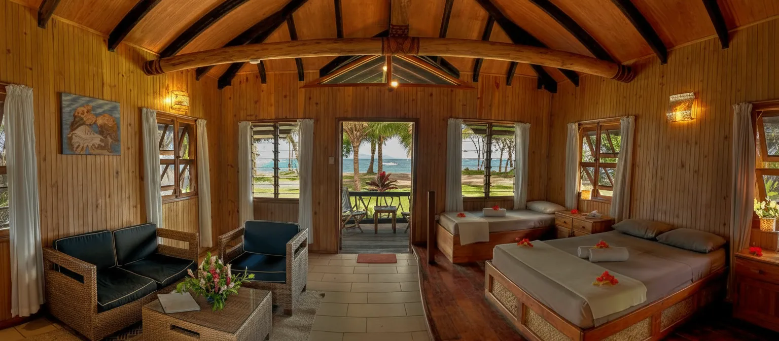 Spacious wooden vilal interior with two beds, seating, and a direct view of the beach and ocean from Uprising Beach Resort.