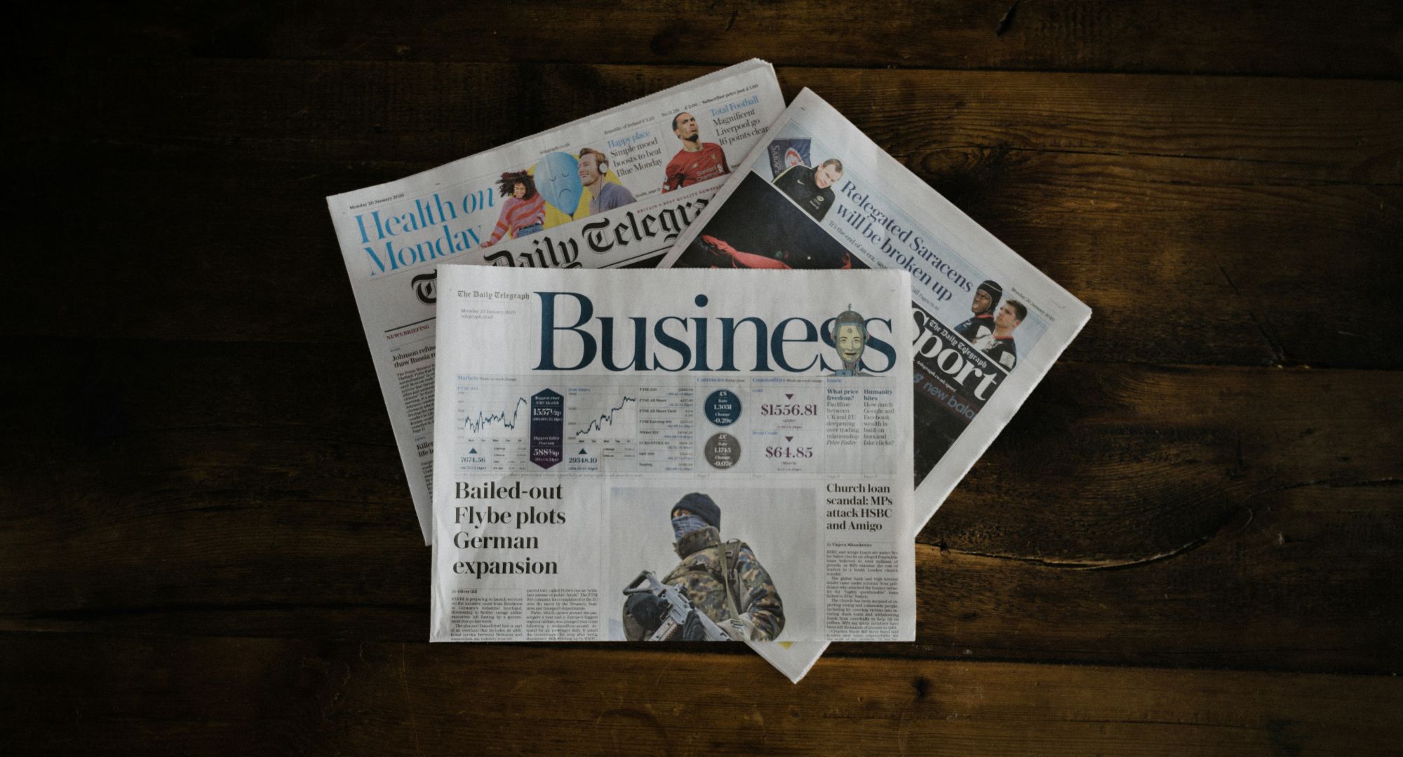 três jornais dobrados um em cima do outro sob uma superfície de madeira