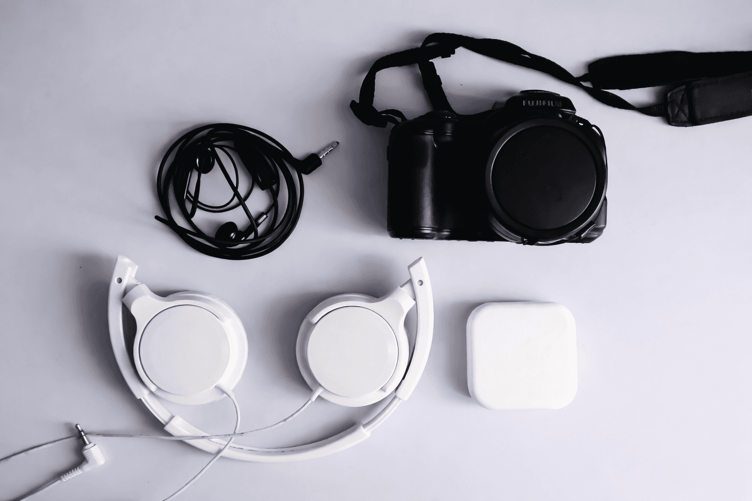 black Fujifilm DSLR camera and white corded headphones