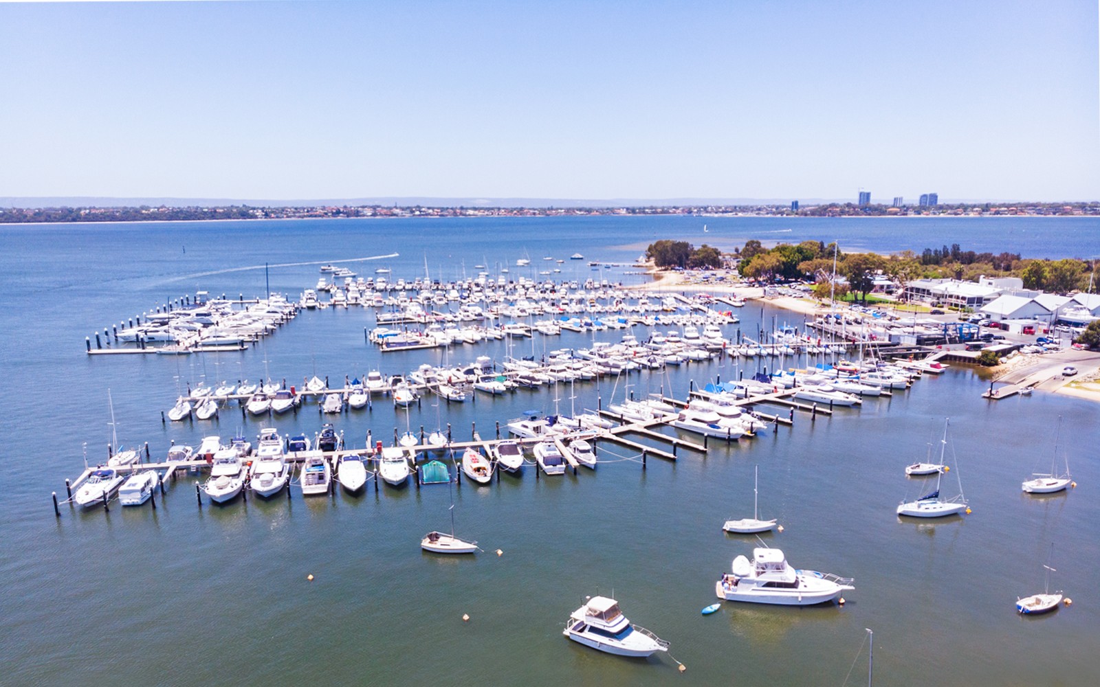 Boats docked at Royal Perth Yacht Club marina with city skyline in the background.