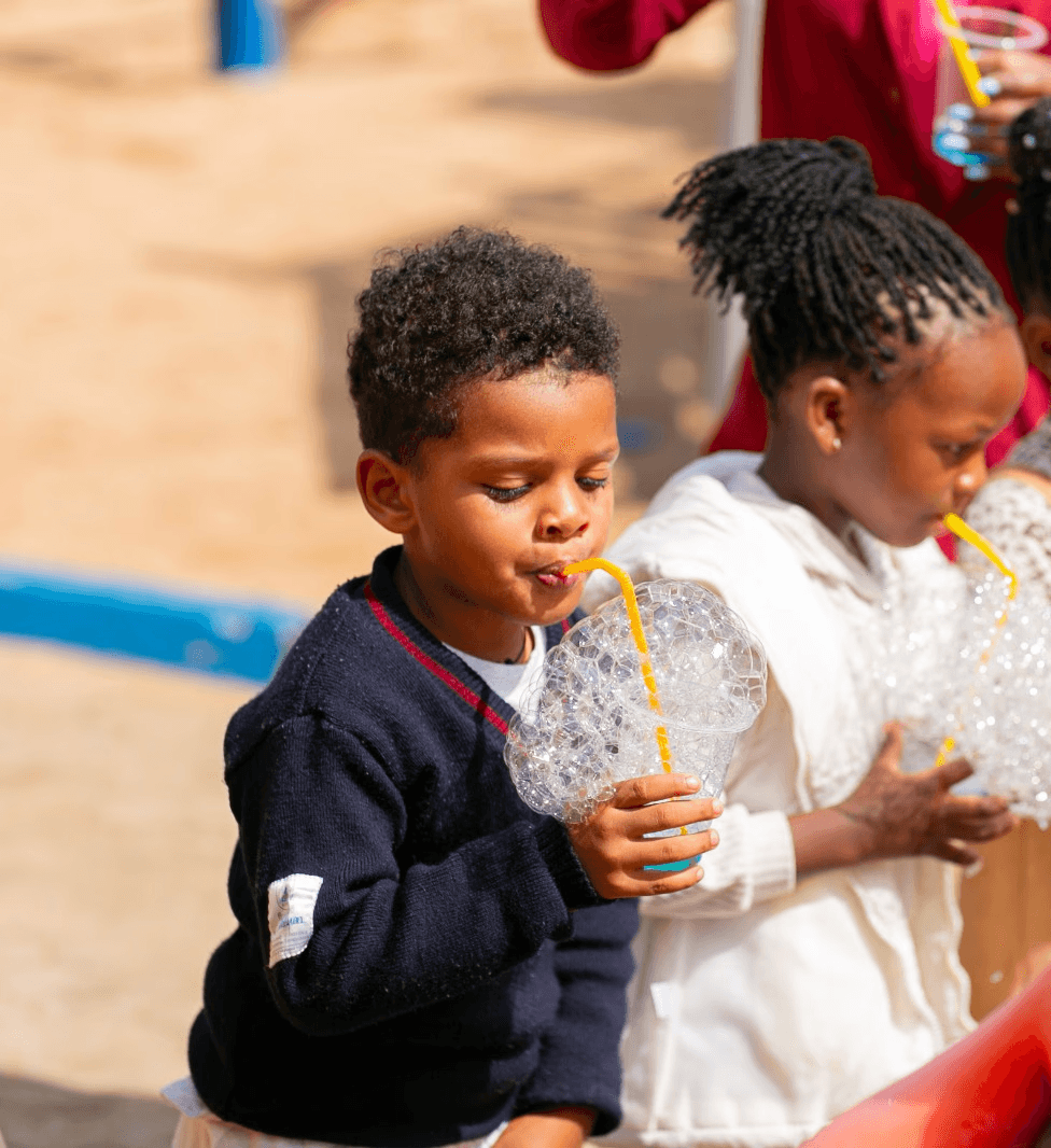 A student wearing a red uniform sits while holding a book in his hands