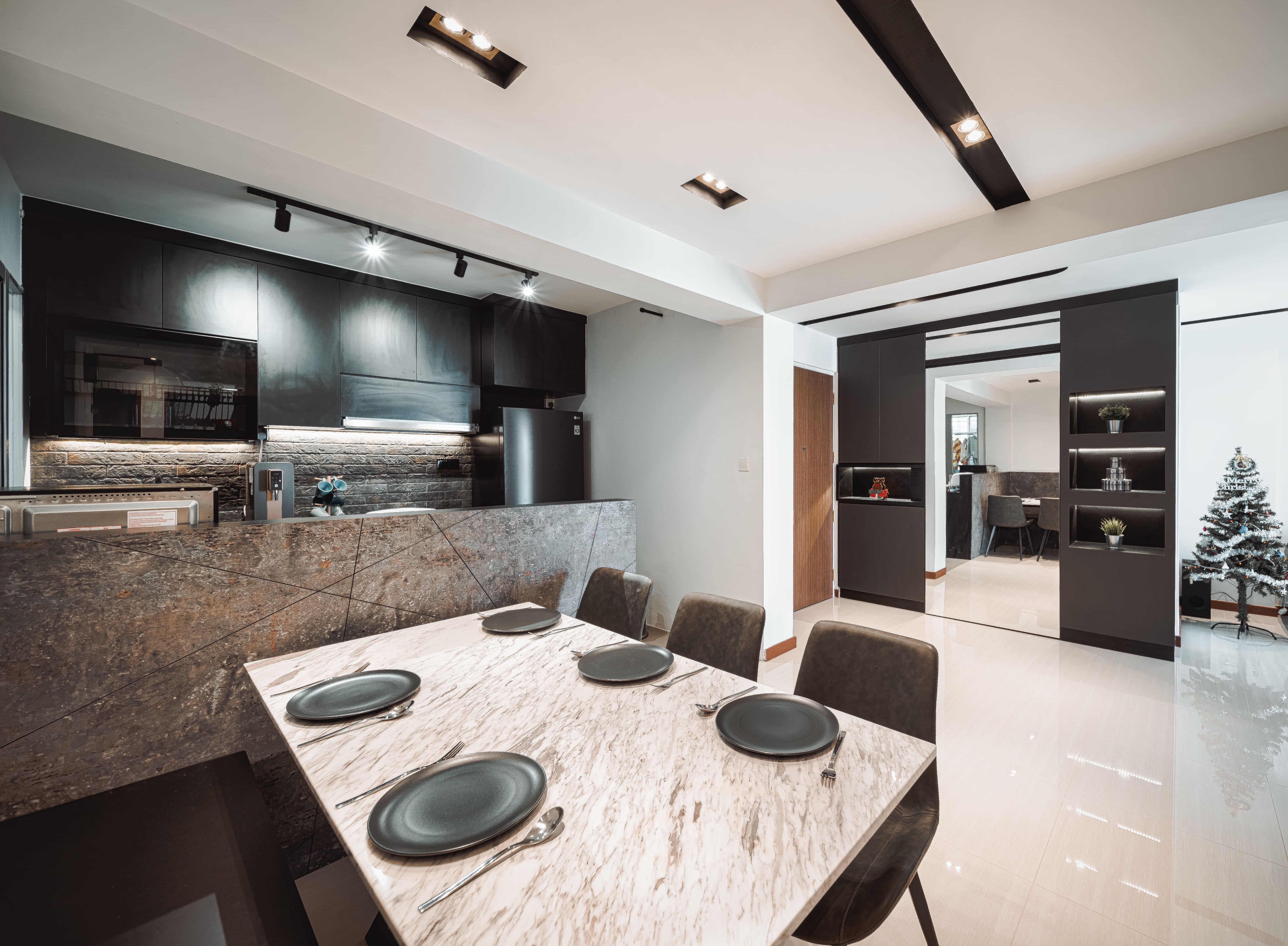 Marble dining table paired with a stone-textured half wall, linking visually with the kitchen design.