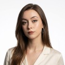 Portrait of a woman with long, smooth hair swept to the side, in a dark t-shirt, on a plain background.