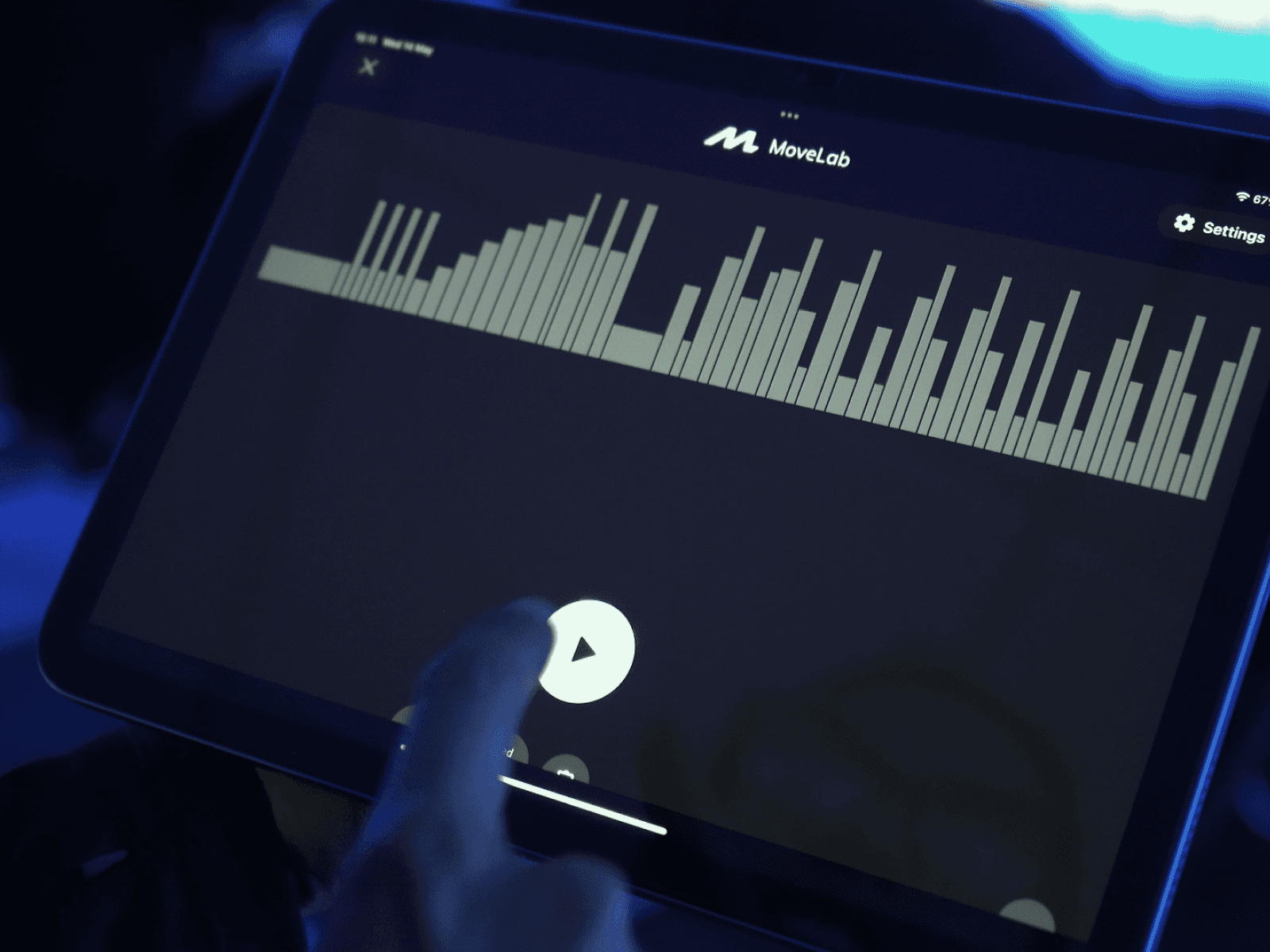 A coach playing the botton "play" in the tablet to start the indoor rowing class.