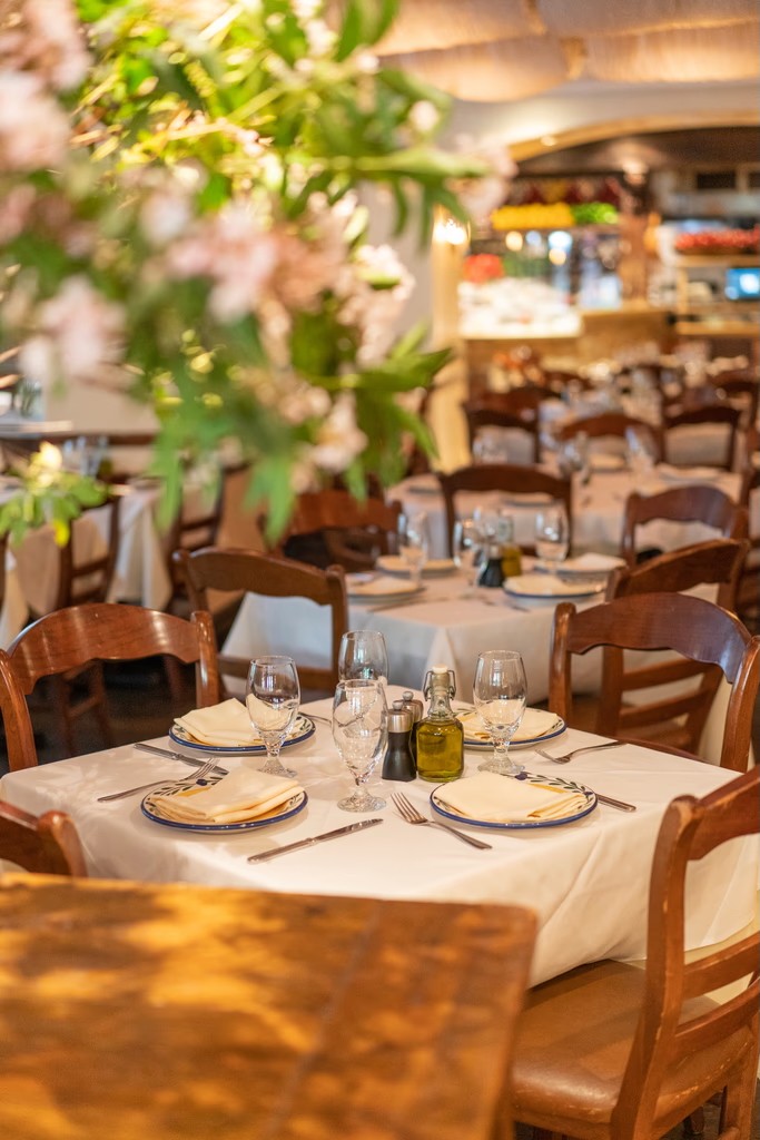 A beautifully set dining table under lush greenery, surrounded by bookshelves filled with books.