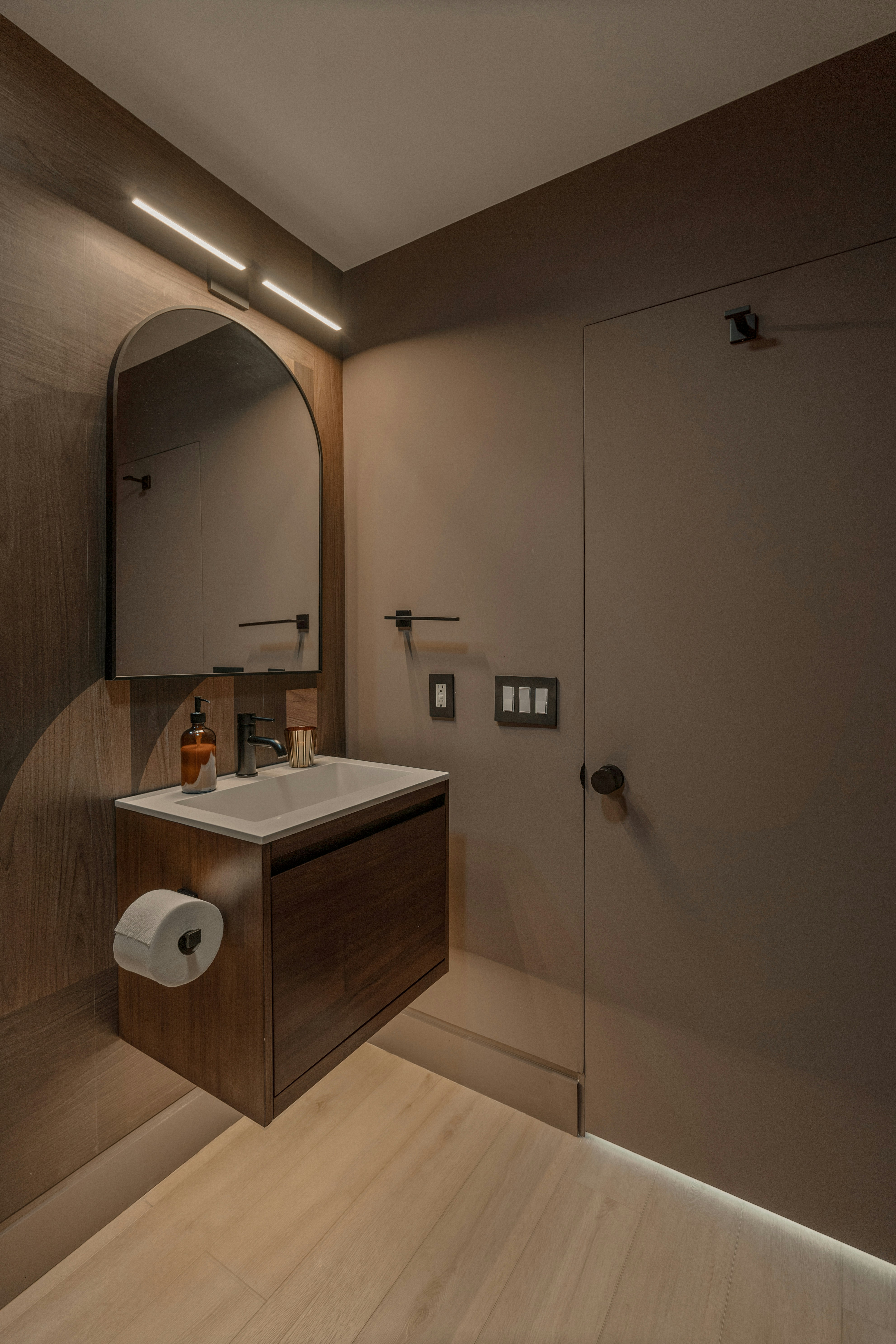 Modern bathroom vanity with arched mirror and wood accents