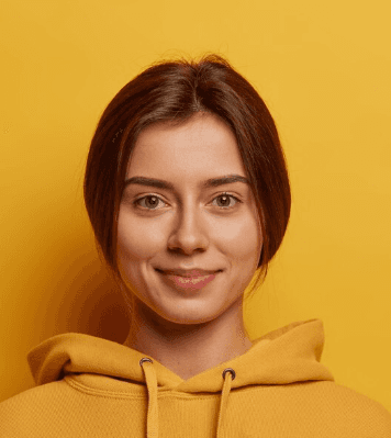 A person wearing a yellow hoodie stands against a matching yellow background, creating a warm and cheerful monochromatic look.