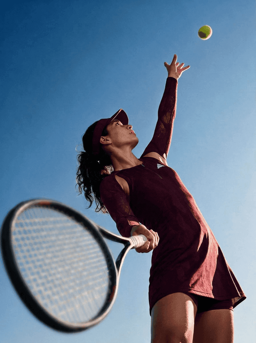 AI-created campaign image of a tennis player in a maroon dress preparing to serve beneath a blue sky.