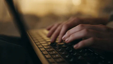 Man sitting in a dimly lit room, wearing a beige shirt and looking contemplative.