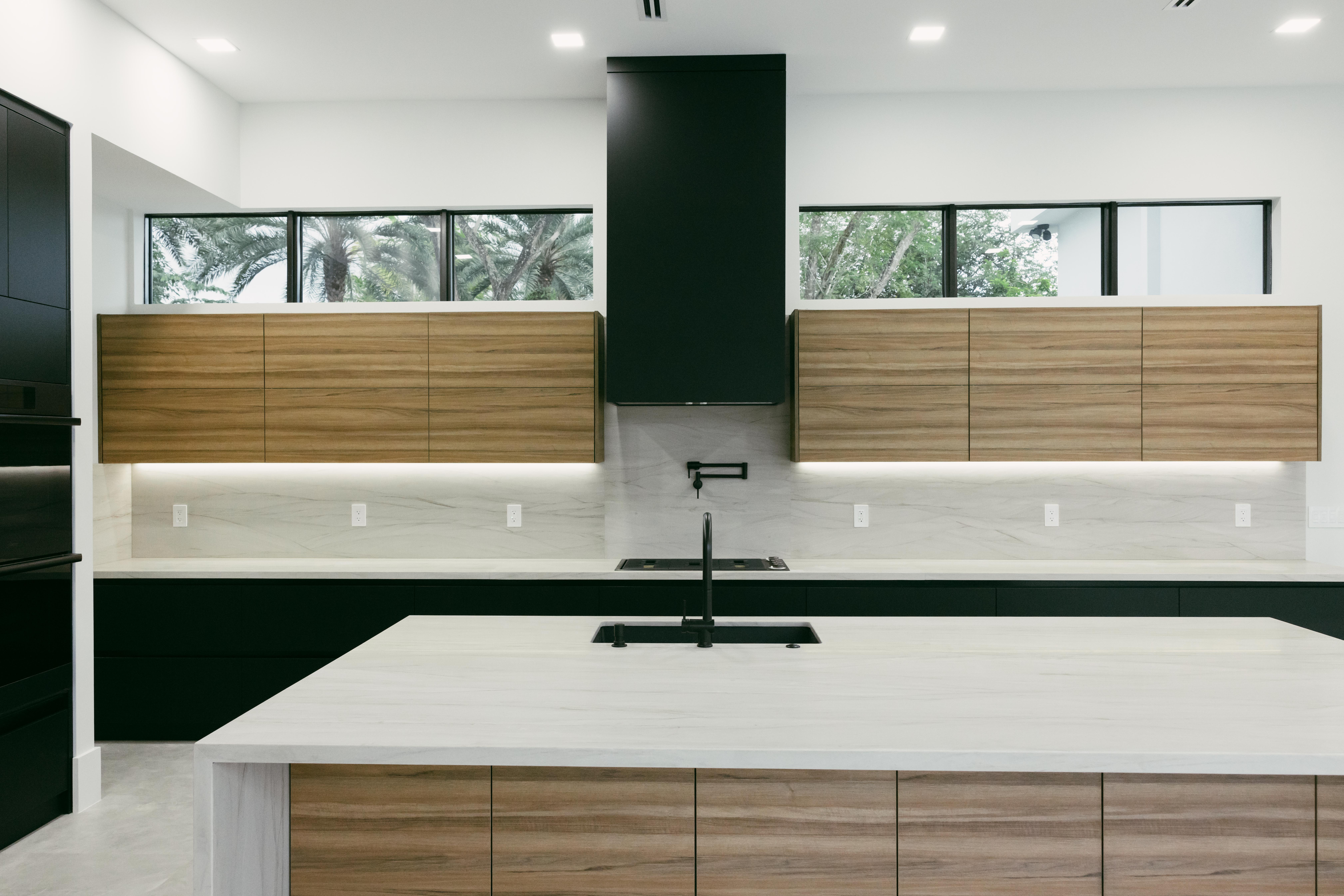 Modern kitchen with wood cabinets, black range hood, and island.