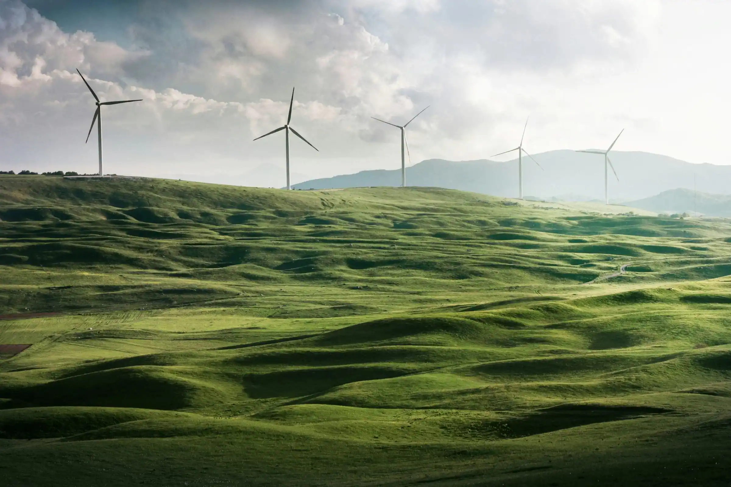 Windkraftanlage in grüner Berglandschaft – Symbol für erneuerbare Energien und Wesentlichkeitsanalyse