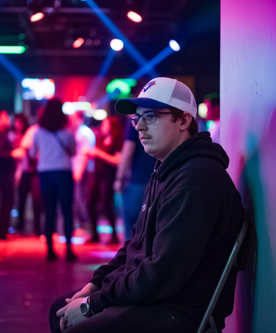 Side profile of the gamer wearing a cap at an event. A character study shot used to establish the 'Persona' of the patient before the transformation, adding depth and realism to the AI-enhanced storytelling.