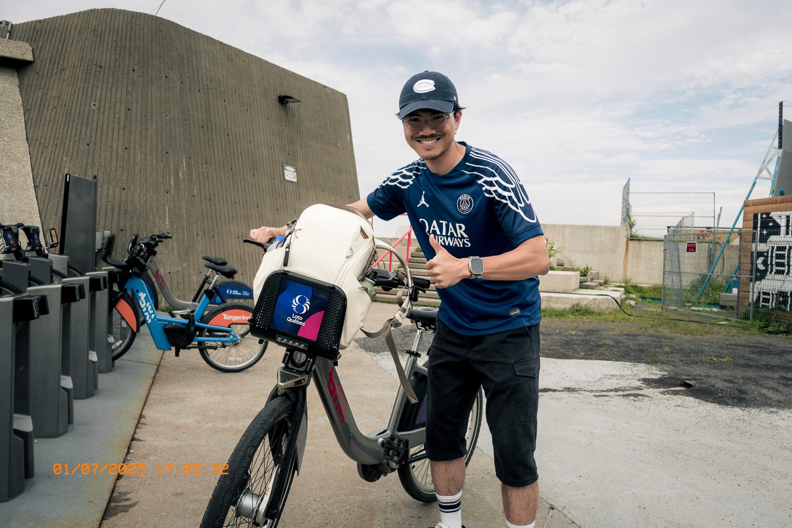 Jeune homme souriant à côté d’un vélo BIXI près d’une station.