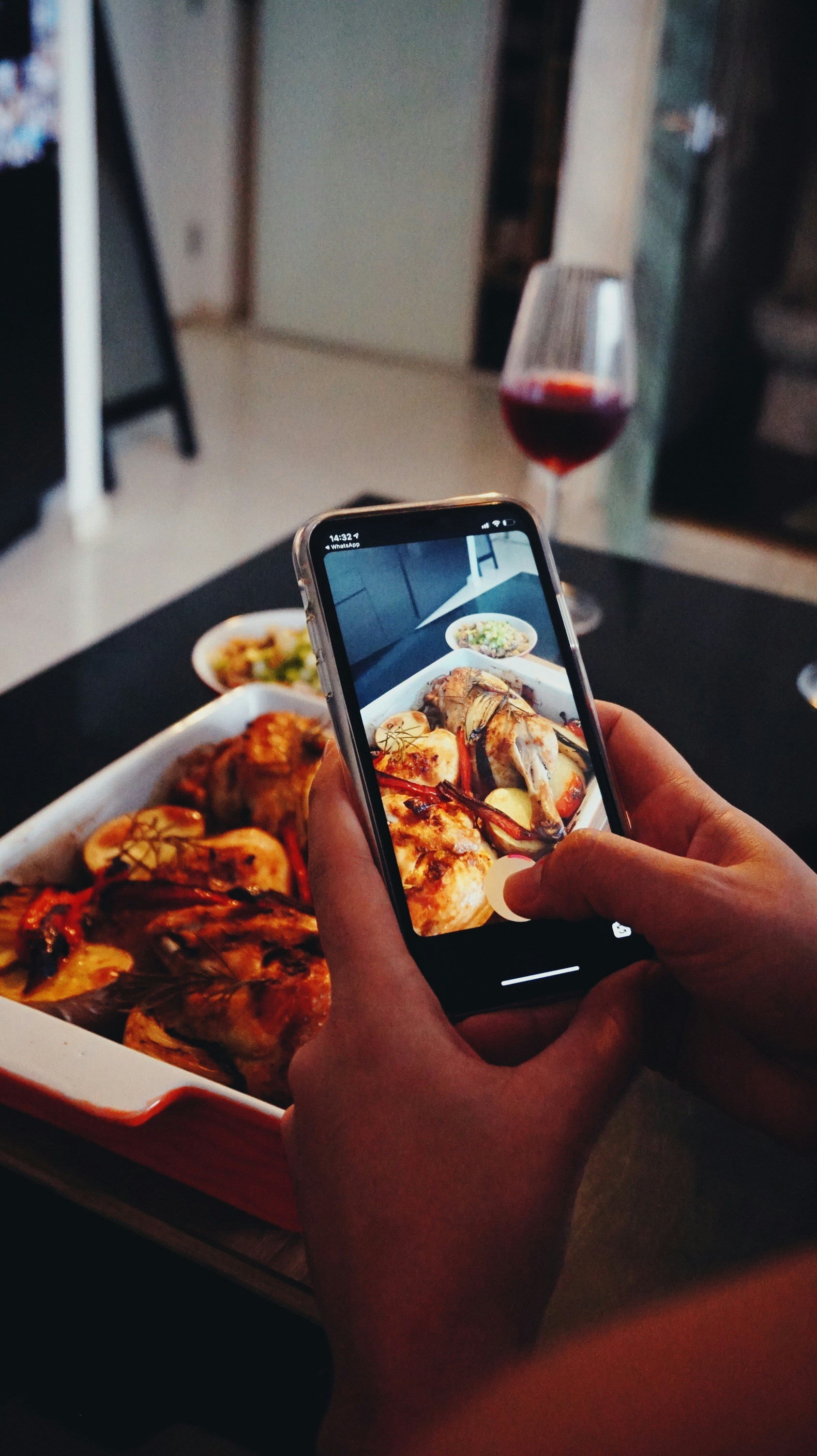 A hand holding a smartphone taking a photo of a meal.