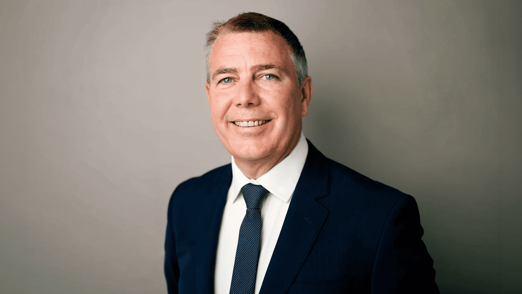 Kim Aiken on a grey background, in smart clothing