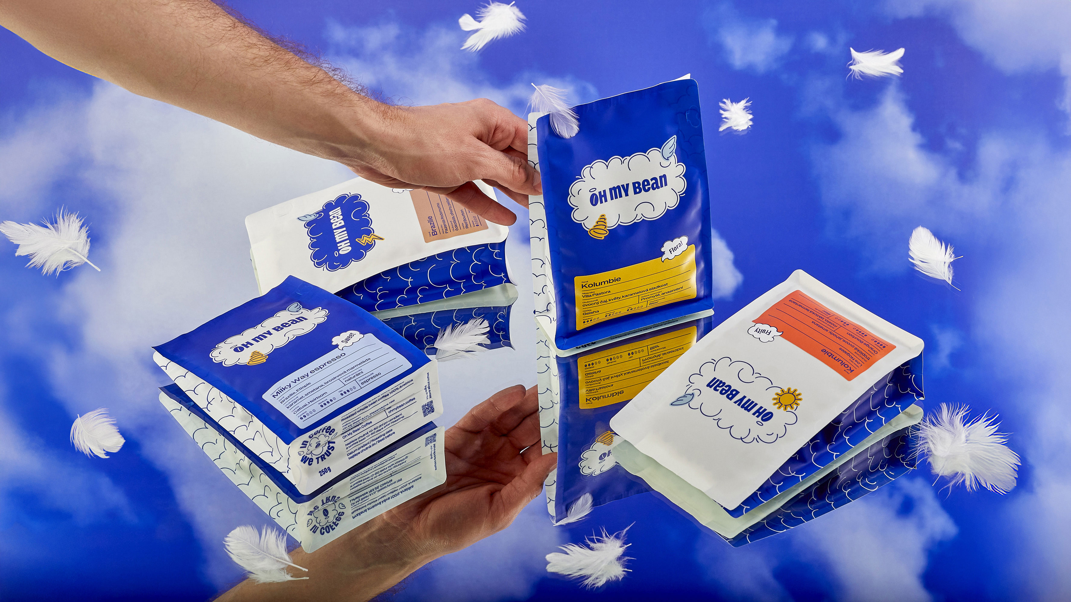 Oh My Bean coffee packaging system by SLOWRAT, showing multiple bag variants held in hands against a sky background