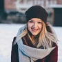 Girl smiling in the snow wearing a scarf and hat.