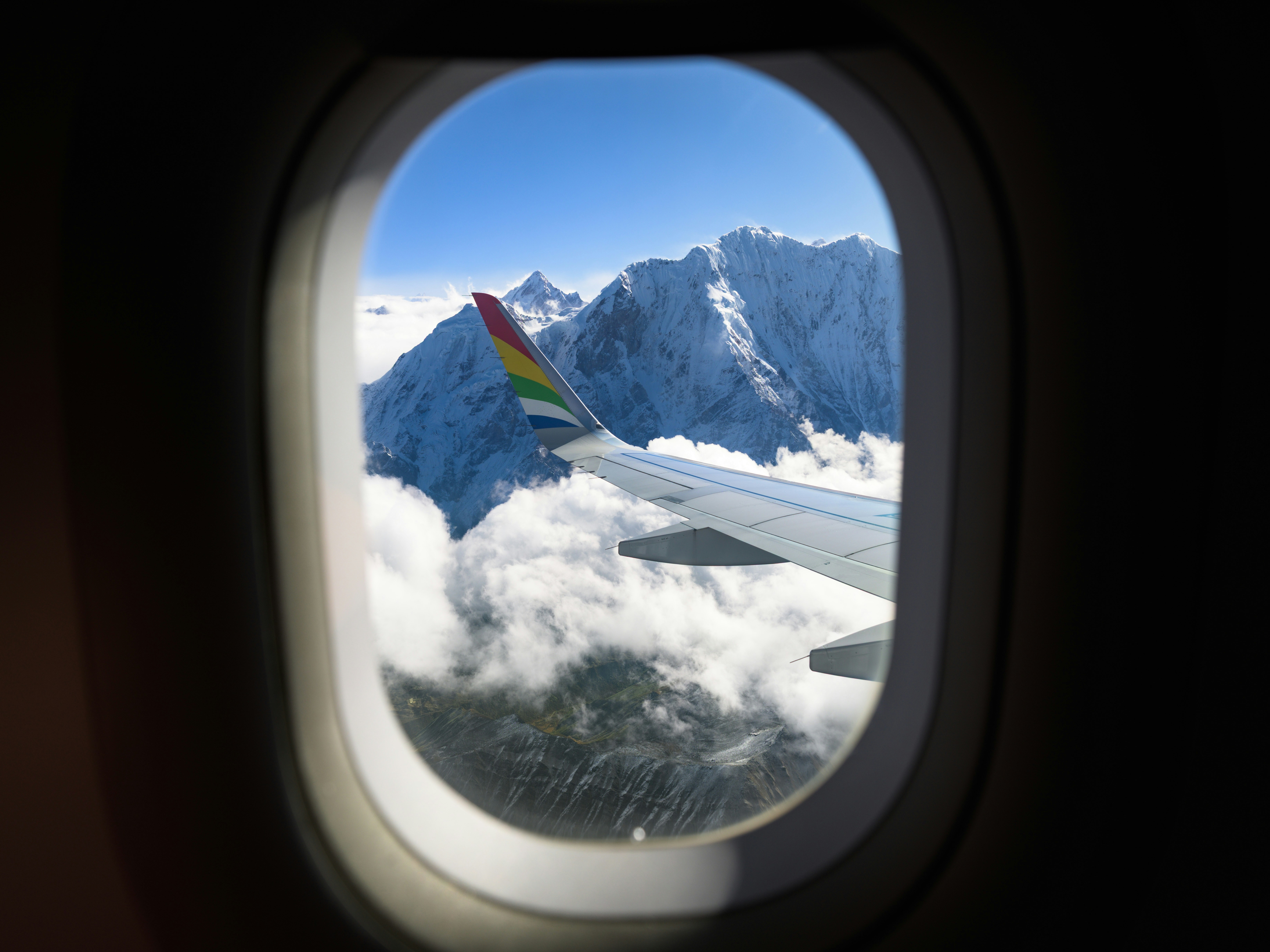 Airplane wing flying over snow-capped mountains