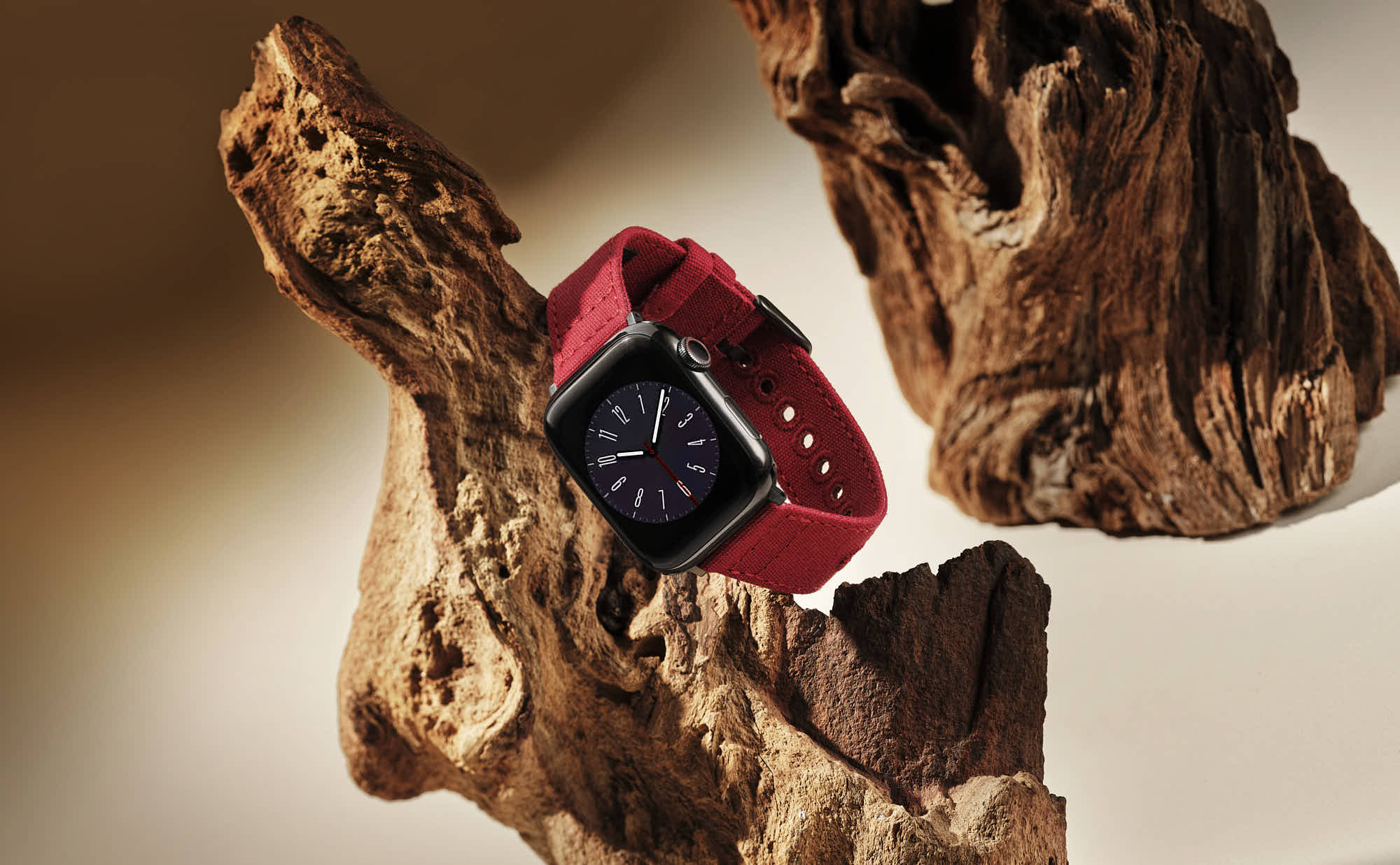 Black smartwatch with red band displayed on rustic wood background.