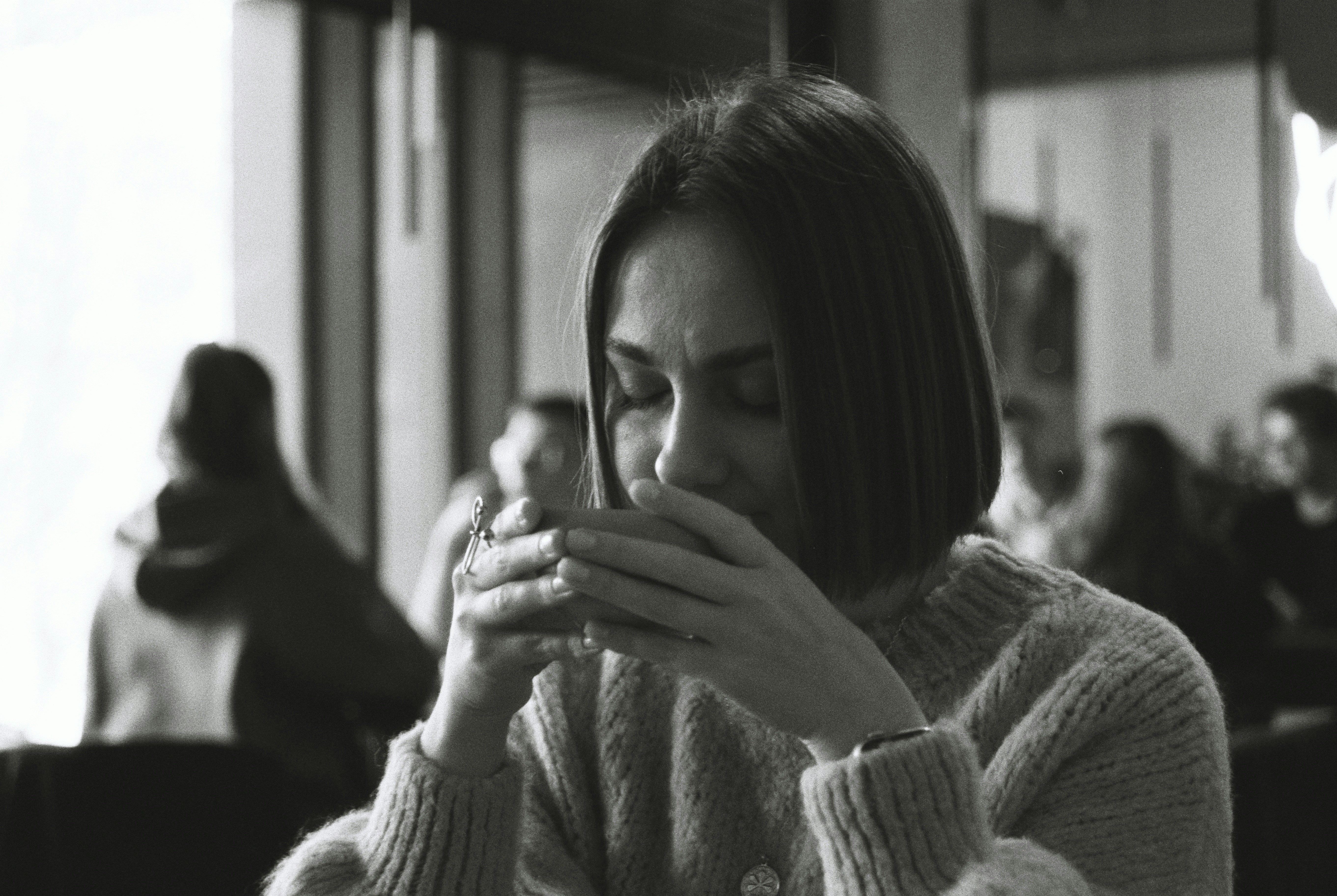 Woman enjoys a warm drink, looking peaceful.