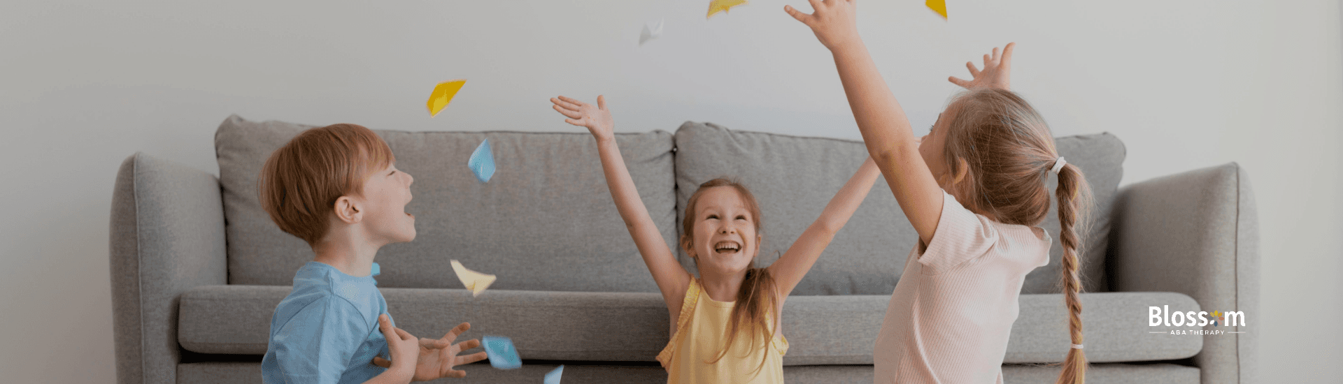 Three children playing with colorful paper indoors.