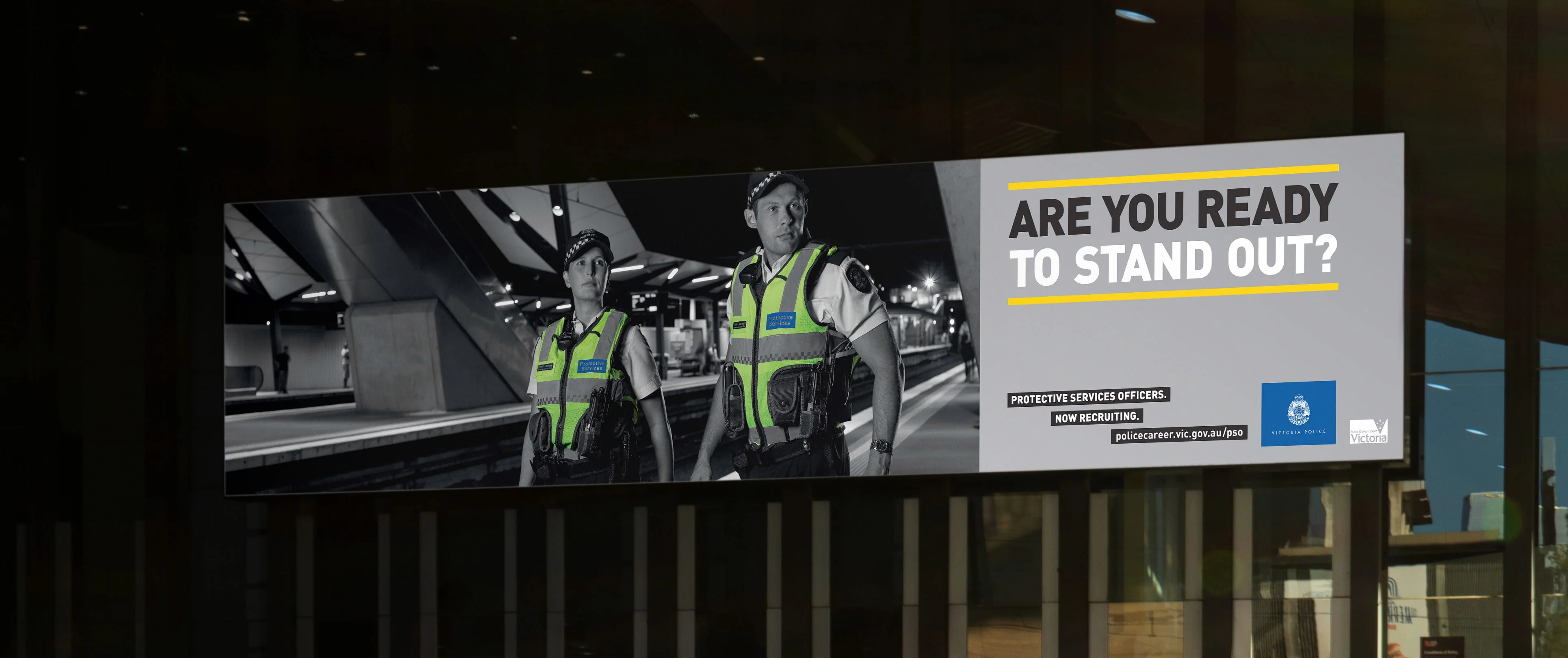 Wide billboard of two Victoria Police protective services officers on a platform asking 'Are you ready to stand out?'