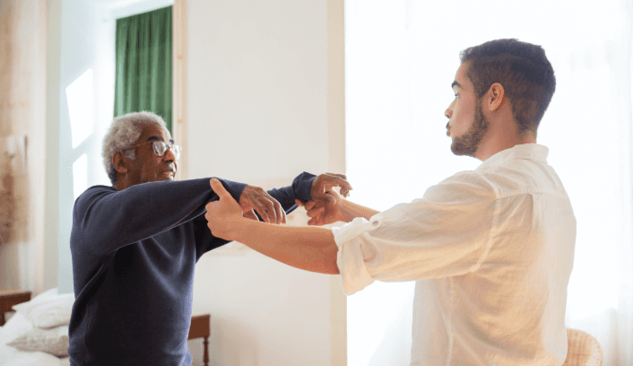 Therapist helping an elderly man with arm mobility exercise.