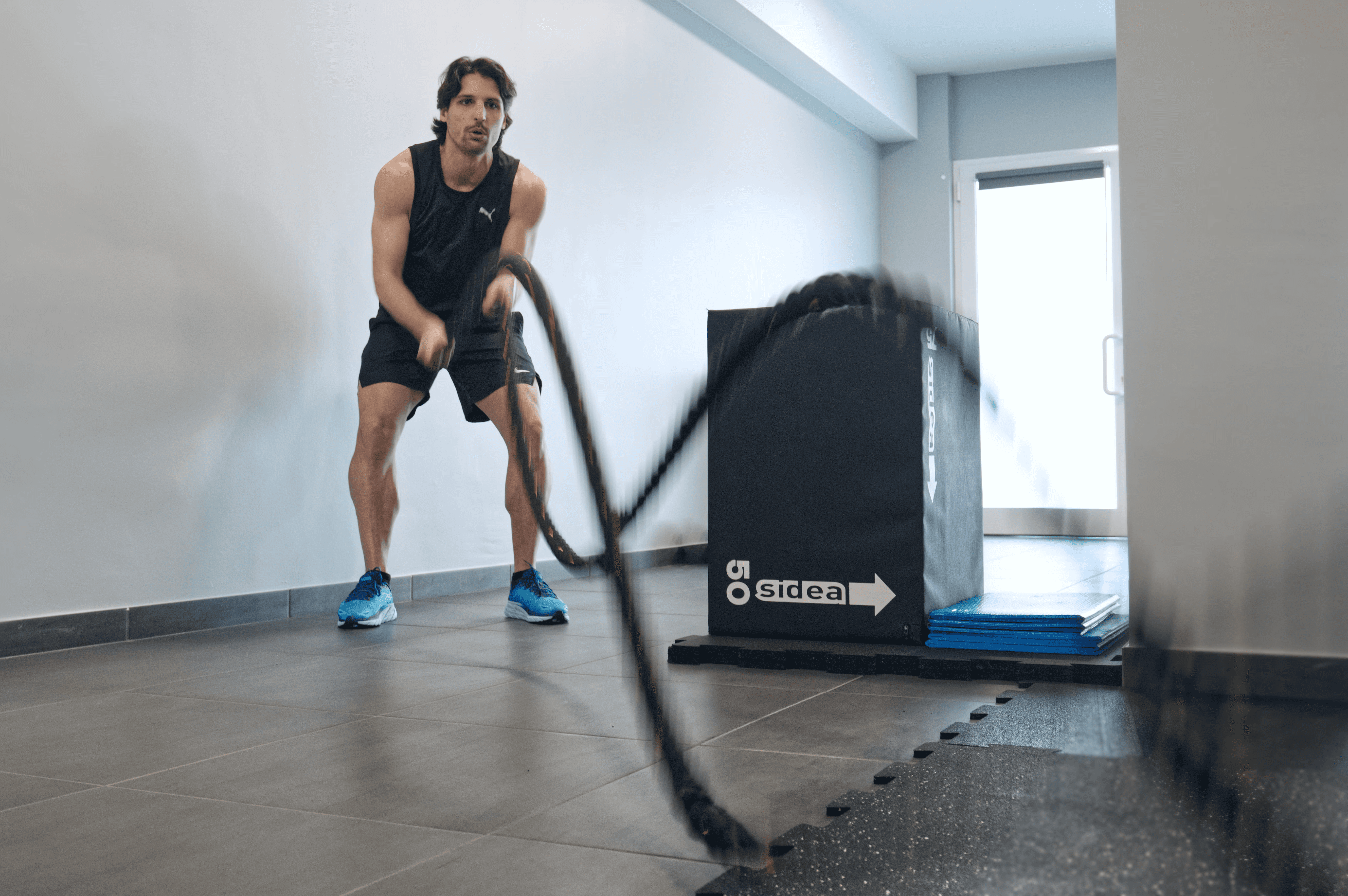 A man stands while two people sit at a table in an office setting, smiling and engaged in conversation. The mood is friendly and collaborative.
