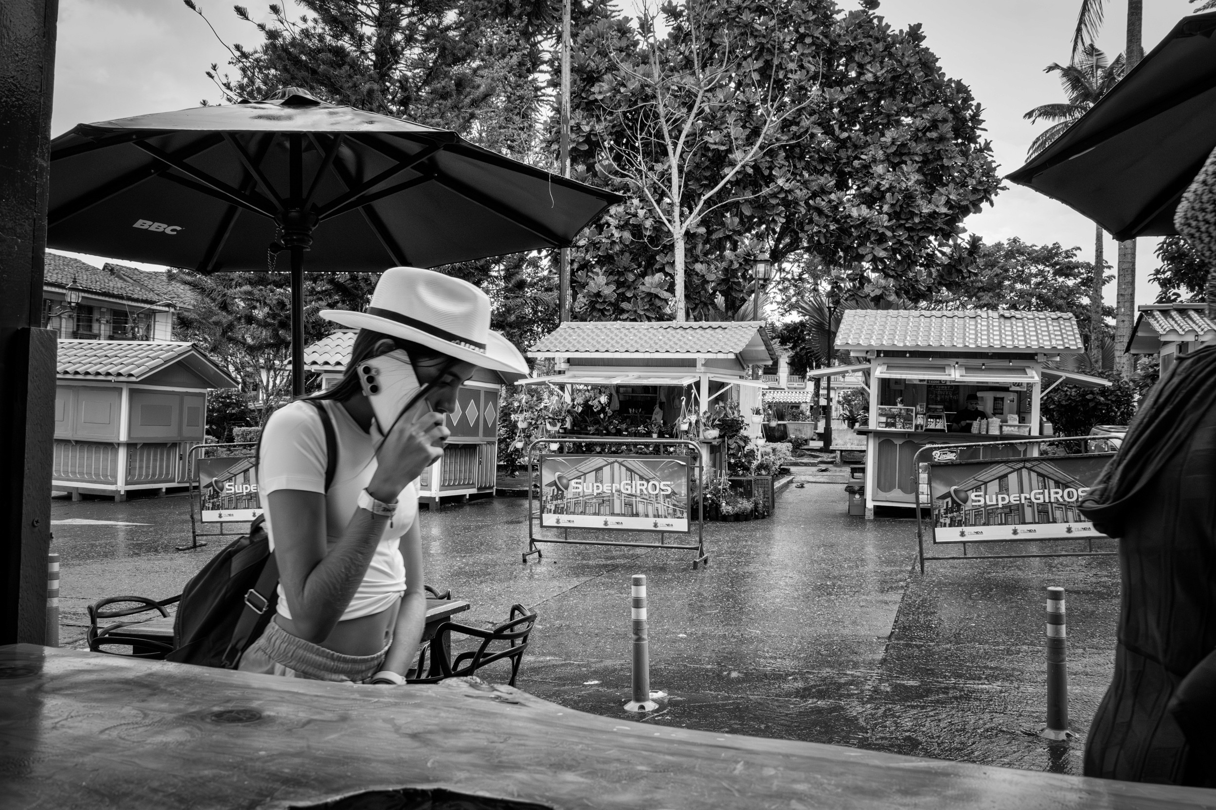 Rainy street scene with people passing by a bar window.