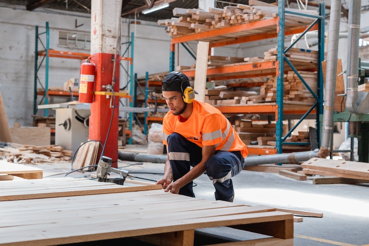 Skilled carpenter constructing a custom export crate using heavy-duty timber in the workshop.