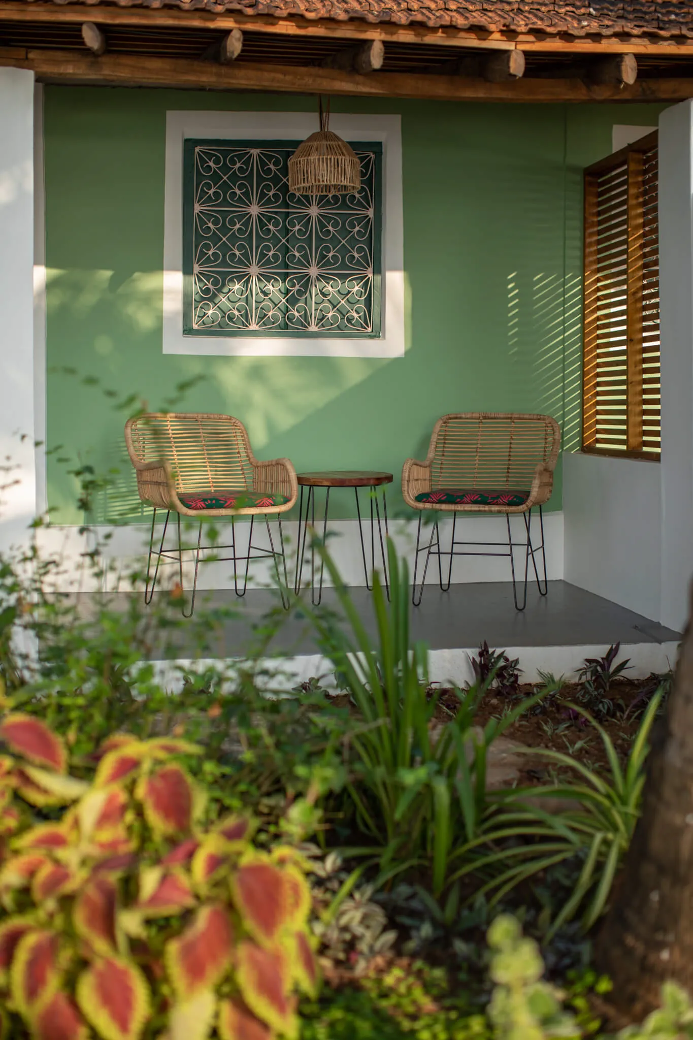 Green cottage porch with cane chairs at Casa Jaali