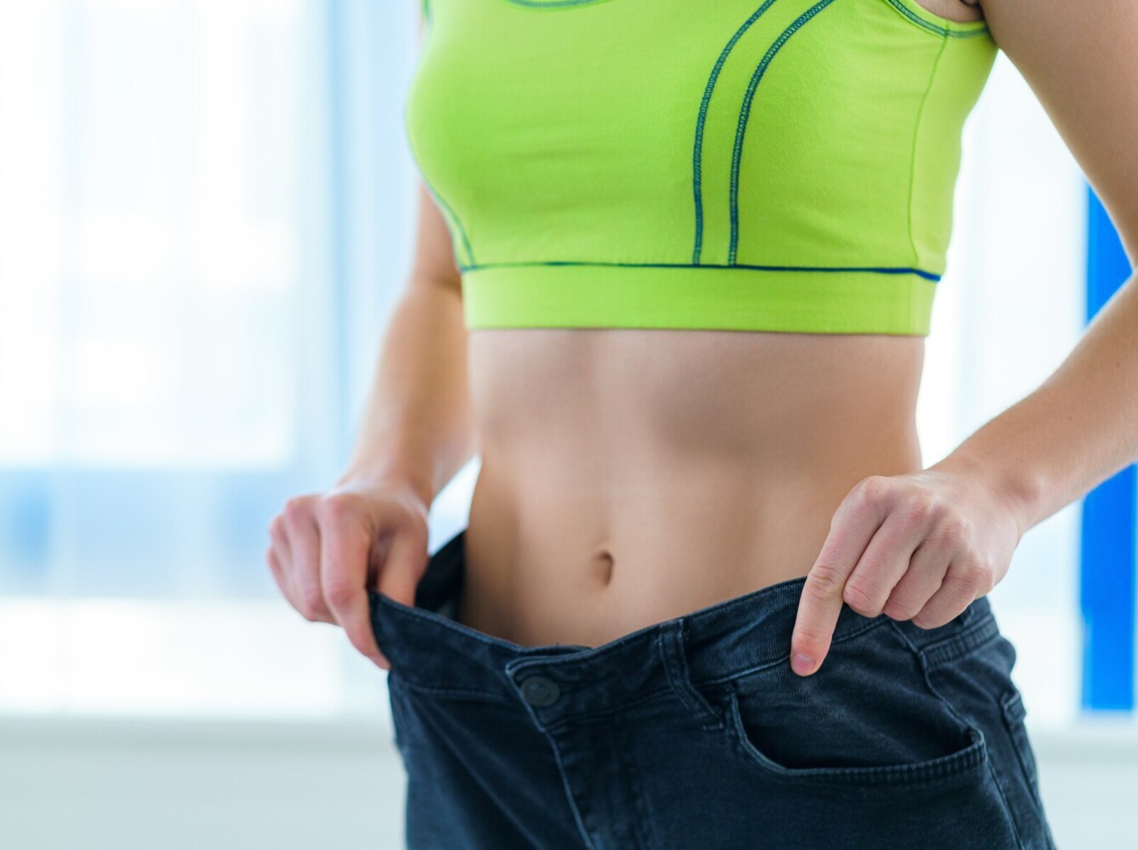 woman checking her weight loss results with an old pair of jeans after following the fastest way to lose weight without exercise